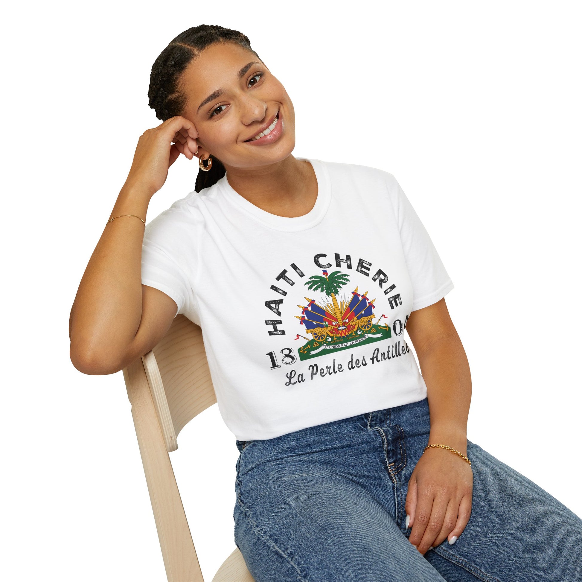 Woman wearing a white t-shirt with 'Haiti Cherie' design, sitting on a chair.